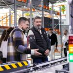 Men observe automated conveyor belt system in warehouse