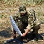 A Ukrainian soldier setting up a Starlink satellite terminal in a field