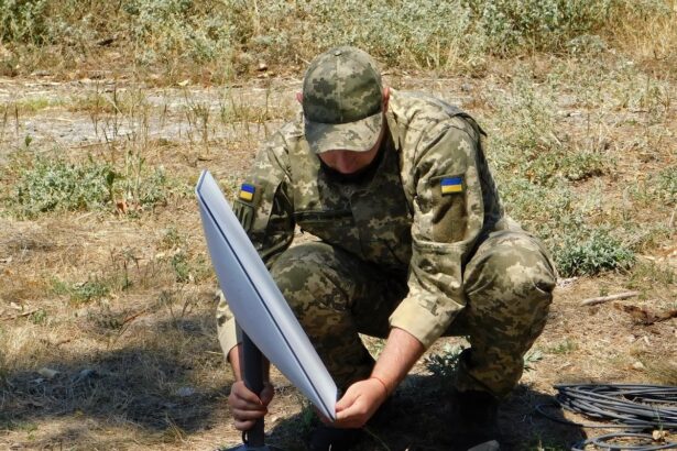A Ukrainian soldier setting up a Starlink satellite terminal in a field