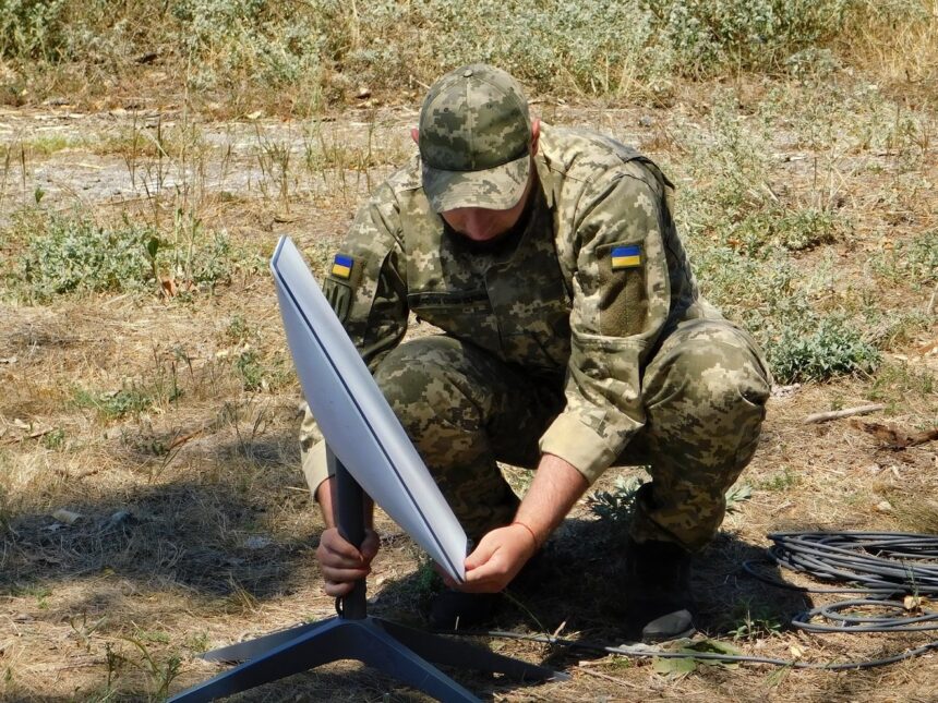 A Ukrainian soldier setting up a Starlink satellite terminal in a field